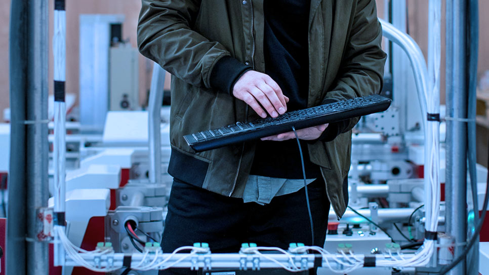 Técnico con un teclado sobre una línea de montaje automatizada durante una auditoría de obsolescencia
